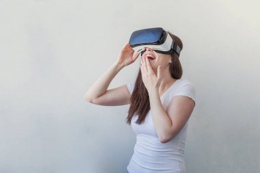 Beyaz arka plan üzerinde sanal gerçeklik Vr gözlük kask kulaklık kullanarak giyen gülümseme genç kadın