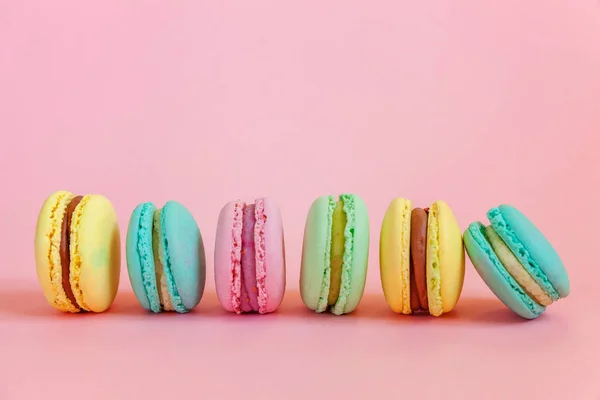 法式甜饼干。最小的食品烘焙概念。粉红色的黄色绿色马卡龙在粉红色的背景 — 图库照片