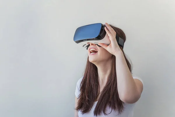 Sonríe mujer joven usando realidad virtual gafas VR casco auriculares sobre fondo blanco — Foto de Stock