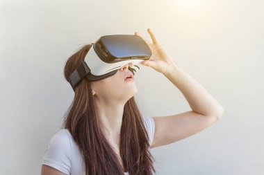 Beyaz arka plan üzerinde sanal gerçeklik Vr gözlük kask kulaklık kullanarak giyen gülümseme genç kadın