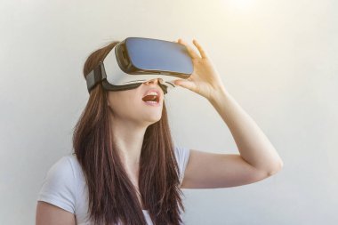 Beyaz arka plan üzerinde sanal gerçeklik Vr gözlük kask kulaklık kullanarak giyen gülümseme genç kadın
