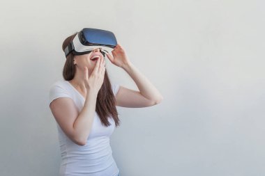 Beyaz arka plan üzerinde sanal gerçeklik Vr gözlük kask kulaklık kullanarak giyen gülümseme genç kadın