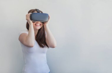 Beyaz arka plan üzerinde sanal gerçeklik Vr gözlük kask kulaklık kullanarak giyen gülümseme genç kadın