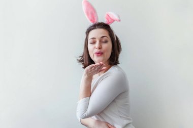 Mutlu Paskalya tatil kutlama bahar kavramı. Beyaz arka plan üzerinde izole Paskalya gününde tavşan kulakları giyen genç kadın