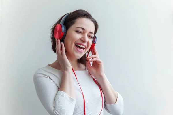 Energy young brunette lady woman listening music in headphones and singing isolated on white background — Stock Photo, Image