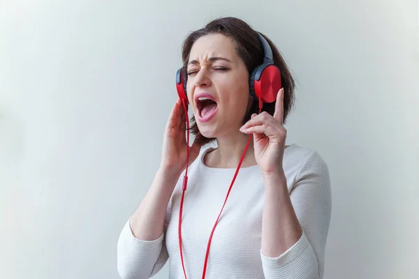 Energia giovane bruna signora donna ascoltando musica in cuffia e cantando isolato su sfondo bianco — Foto Stock