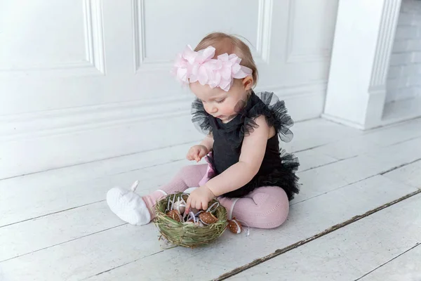 Menina pequena usando coroa de primavera no dia de Páscoa e brincando com ovos pintados — Fotografia de Stock