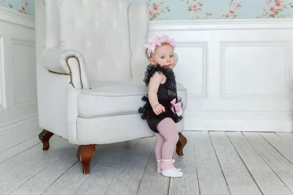 Parlak ışık oturma odasında gülümseyen ve gülüyor sandalyede yakın ayakta küçük bebek kız — Stok fotoğraf