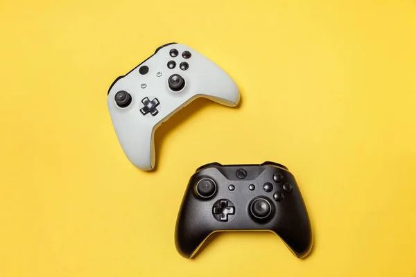 Branco e preto dois joystick no fundo amarelo. Concorrência de jogos de computador conceito de confronto de controle de videogame — Fotografia de Stock