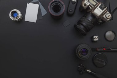 DSLR kamera sistemi, kamera Temizleme Kiti, koyu siyah masa arka planda objektif ve kamera aksesuarı ile fotoğrafçı çalışma alanı
