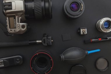 DSLR kamera sistemi, kamera Temizleme Kiti, koyu siyah masa arka planda objektif ve kamera aksesuarı ile fotoğrafçı çalışma alanı