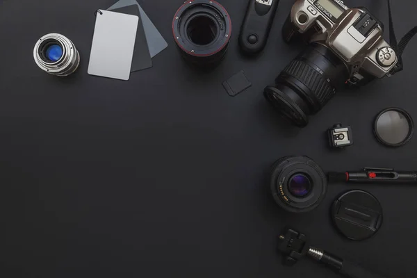 Fotograf-Arbeitsplatz mit DSLR-Kamerasystem, Kamera-Reinigungs-Set, Objektiv und Kamerazubehör auf dunkelschwarzem Tischhintergrund — Stockfoto