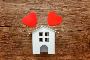 Ahşap bir arka planda kırmızı kalpler ile minyatür beyaz oyuncak ev