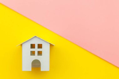 Sarı ve pembe renkli trendy modern pastel arka planda izole minyatür beyaz oyuncak ev ile sadece minimal tasarım