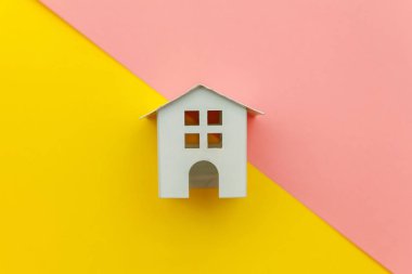 Sarı ve pembe renkli trendy modern pastel arka planda izole minyatür beyaz oyuncak ev ile sadece minimal tasarım