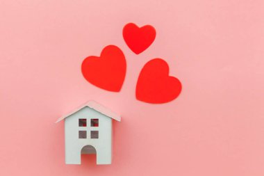 Pembe pastel renkli trendy arka planda izole kırmızı kalp ile minyatür beyaz oyuncak ev ile sadece minimal tasarım