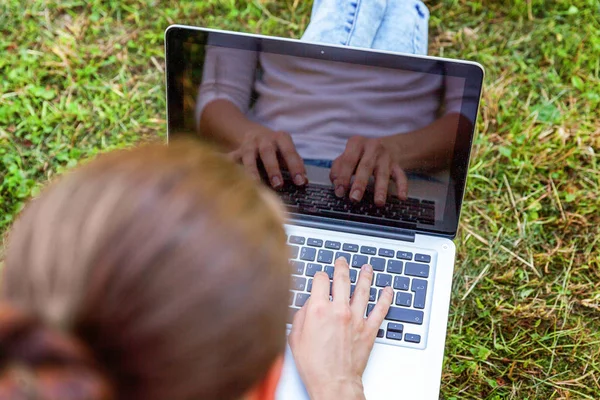 Dizüstü pc bilgisayar üzerinde çalışan Şehir Parkı yeşil çim Çimenlikte oturan genç kadın. Serbest iş kavramı
