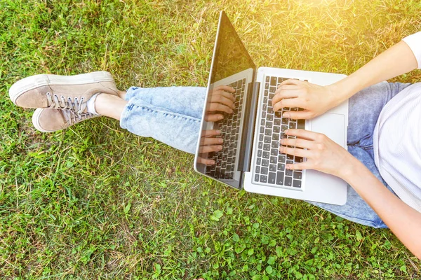 Kadın ayakları üzerinde yeşil çim şehir Park, dizüstü pc bilgisayar üzerinde çalışan eller çimen. Serbest iş kavramı