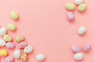 Mutlu Paskalya konsepti. Paskalya şekeri çikolata yumurta ve Jellybean tatlılar trendy pastel pembe arka planda izole. Basit minimalizm düz üst görünüm kopya alanı yatıyordu