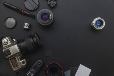 DSLR kamera sistemi, kamera Temizleme Kiti, koyu siyah masa arka planda objektif ve kamera aksesuarı ile fotoğrafçı çalışma alanı