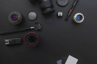 DSLR kamera sistemi, kamera Temizleme Kiti, koyu siyah masa arka planda objektif ve kamera aksesuarı ile fotoğrafçı çalışma alanı