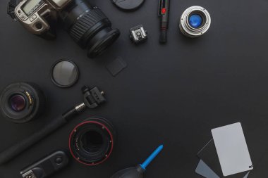 DSLR kamera sistemi, kamera Temizleme Kiti, koyu siyah masa arka planda objektif ve kamera aksesuarı ile fotoğrafçı çalışma alanı