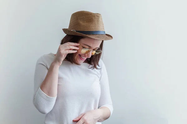 Simple studio portrait of hipster fashion smiling girl in trendy yelow sunglasses and hat isolated on white background