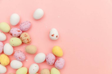 Mutlu Paskalya konsepti. Paskalya şekeri çikolata yumurta ve Jellybean tatlılar trendy pastel pembe arka planda izole. Basit minimalizm düz üst görünüm kopya alanı yatıyordu