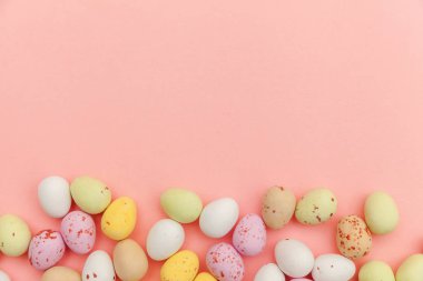 Mutlu Paskalya konsepti. Paskalya şekeri çikolata yumurta ve Jellybean tatlılar trendy pastel pembe arka planda izole. Basit minimalizm düz üst görünüm kopya alanı yatıyordu