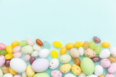 Mutlu Paskalya konsepti. Paskalya şeker çikolata yumurta ve jellybean tatlılar trendy pastel mavi arka plan izole. Basit minimalizm düz üst görünüm kopyalama alanı yatıyordu