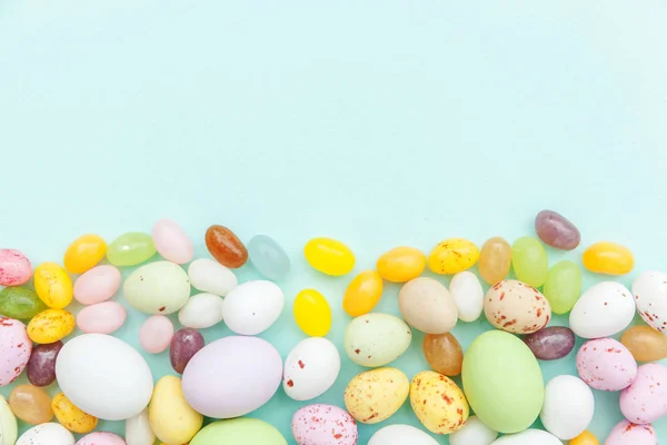 Feliz concepto de Pascua. Huevos de chocolate con caramelos de Pascua y dulces de gelatina aislados sobre un fondo azul pastel de moda. Minimalismo simple plano laico vista superior copia espacio — Foto de Stock