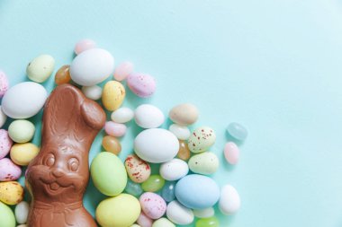 Mutlu Paskalya konsepti. Paskalya şeker çikolata yumurta tavşan ve jellybean tatlılar trendy pastel mavi arka plan izole. Basit minimalizm düz üst görünüm kopyalama alanı yatıyordu