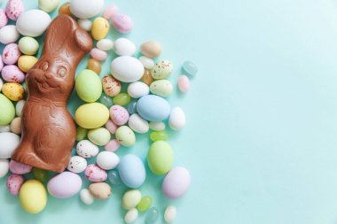 Mutlu Paskalya konsepti. Paskalya şeker çikolata yumurta tavşan ve jellybean tatlılar trendy pastel mavi arka plan izole. Basit minimalizm düz üst görünüm kopyalama alanı yatıyordu