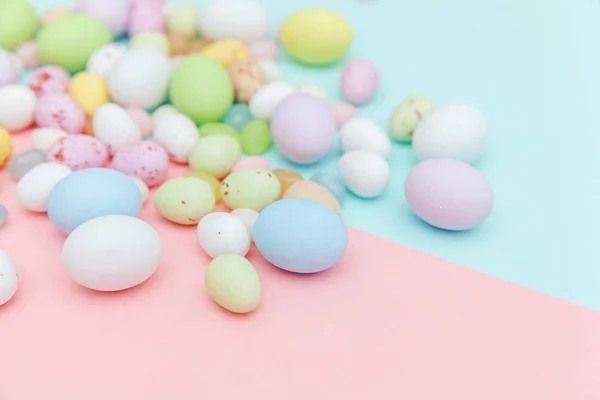 Feliz concepto de Pascua. Huevos de chocolate con caramelos de Pascua y dulces de gelatina aislados sobre un fondo rosa azul pastel de moda. Minimalismo simple plano laico vista superior copia espacio — Foto de Stock