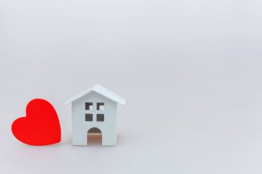Beyaz arka planda izole kırmızı kalp ile minyatür beyaz oyuncak ev ile sadece minimal tasarım