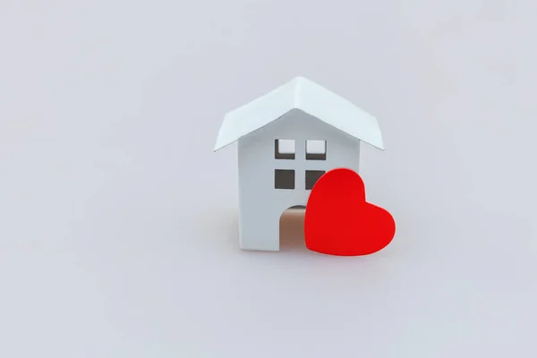 Design simplesmente mínimo com casa de brinquedo branca em miniatura com coração vermelho isolado no fundo branco — Fotografia de Stock