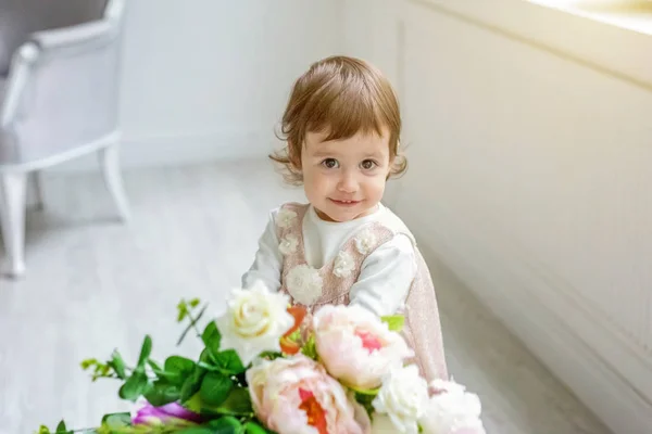 Klein meisje zitten spelen met bloemen boeket — Stockfoto