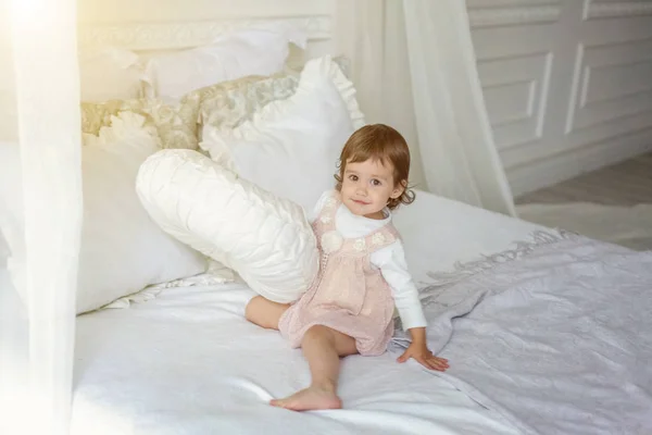 Menina bonito pulando na cama branca — Fotografia de Stock