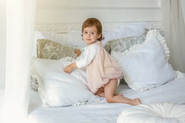 Petite fille mignonne sautant sur lit blanc — Photo