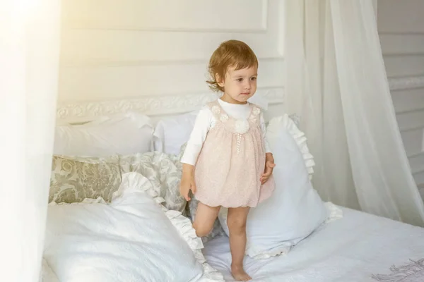 Schattig klein meisje springen op witte bed — Stockfoto