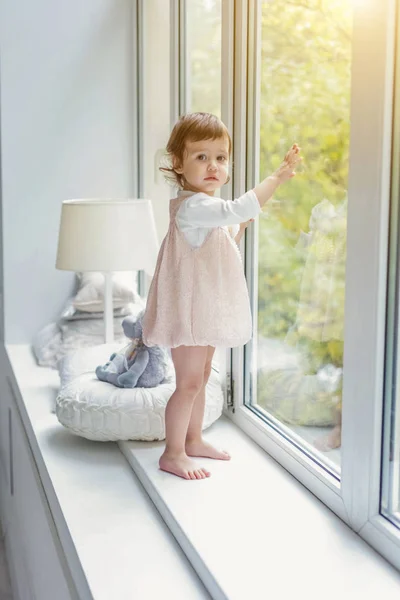 Petite fille debout sur le rebord de la fenêtre — Photo