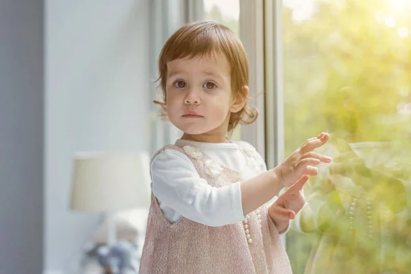 Liten flicka som står på fönsterbrädan — Stockfoto