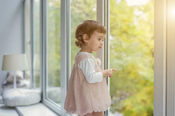 Petite fille debout sur le rebord de la fenêtre — Photo