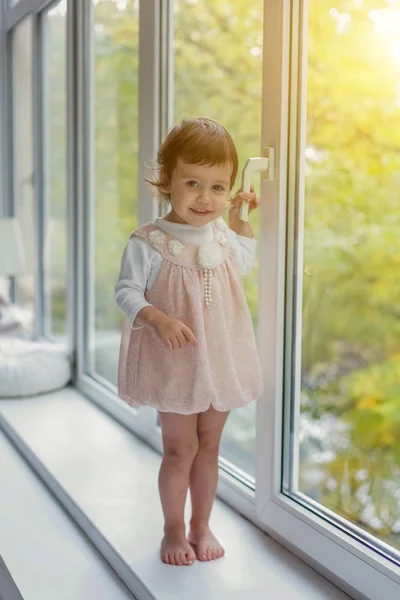 Little girl standing on window sill