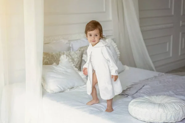 Schattig klein meisje springen op witte bed — Stockfoto