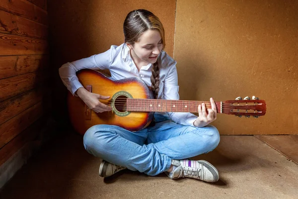 Молода хіпстерка сидить на підлозі і грає на гітарі вдома — стокове фото