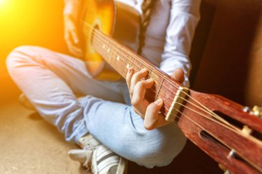 Genç hippi kadın elleri evde gitar çalıyor. Genç kız odasında şarkı çalmayı ve şarkı yazmayı öğreniyor.