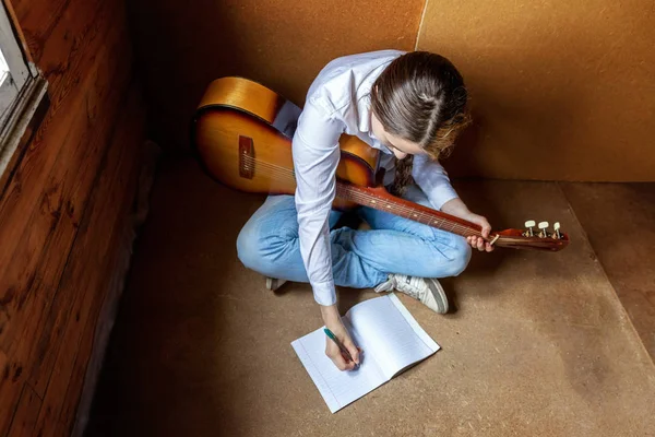 Jovem hipster mulher sentado no chão e tocando guitarra em casa — Fotografia de Stock