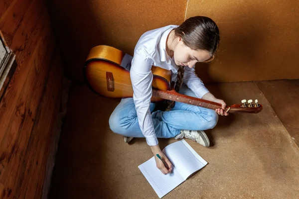 Jovem hipster mulher sentado no chão e tocando guitarra em casa — Fotografia de Stock