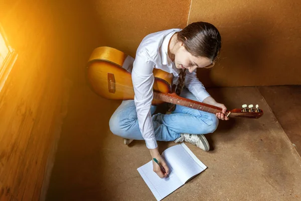 Jovem hipster mulher sentado no chão e tocando guitarra em casa — Fotografia de Stock